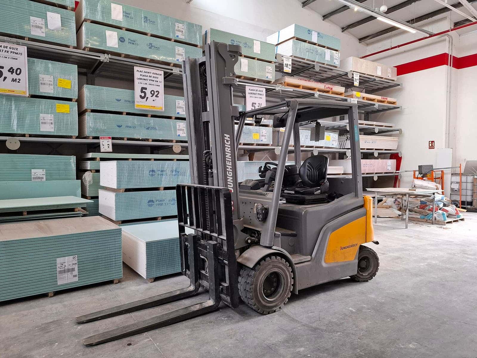 Forklift elektrik abu-abu di lorong toko bahan bangunan