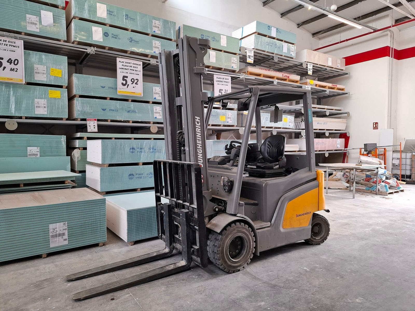 Forklift elektrik abu-abu di lorong toko bahan bangunan