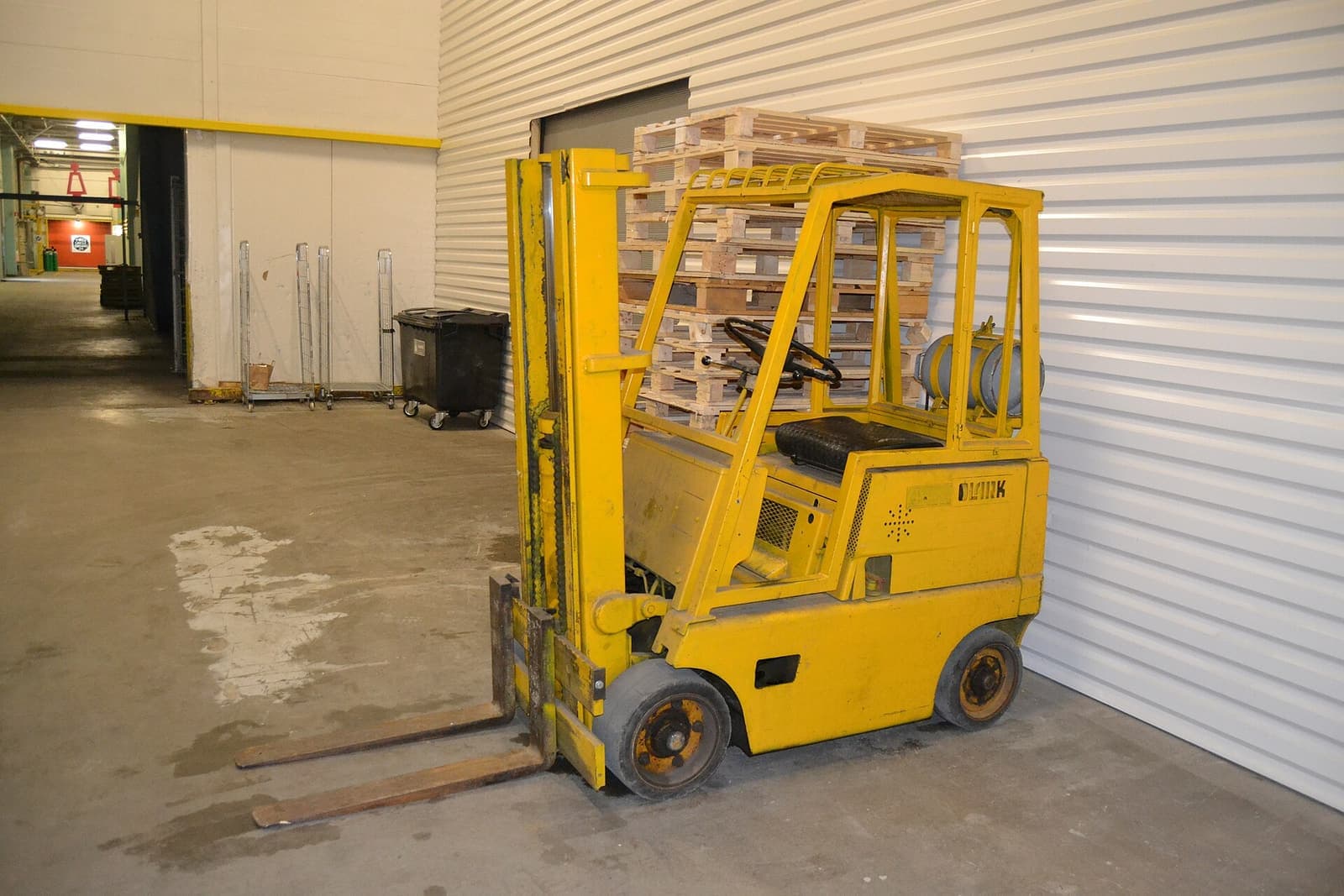 Forklift kuning terparkir di depan pintu gudang